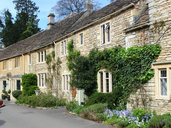 A long honey-stone range with mullioned windows, climbing plants and a spring border on a village lane east of Bath
