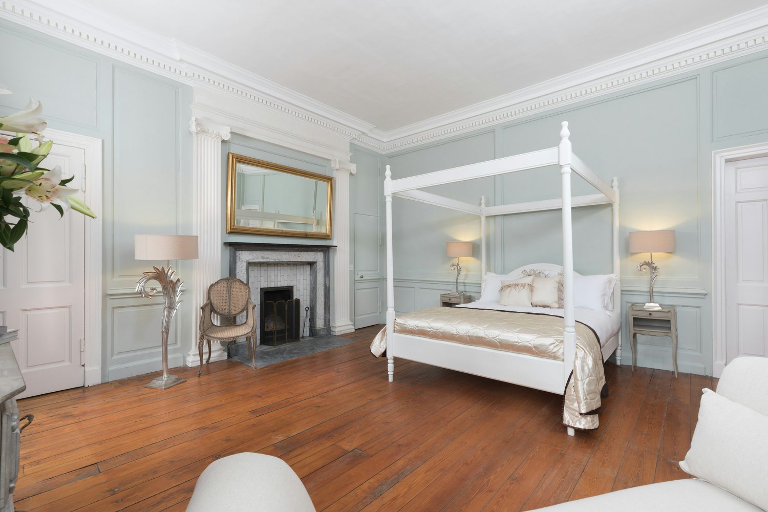 A panelled Georgian bedroom with a stone fireplace and bare floorboards, tidied and lit for the photographs Walcot Property takes in the first week