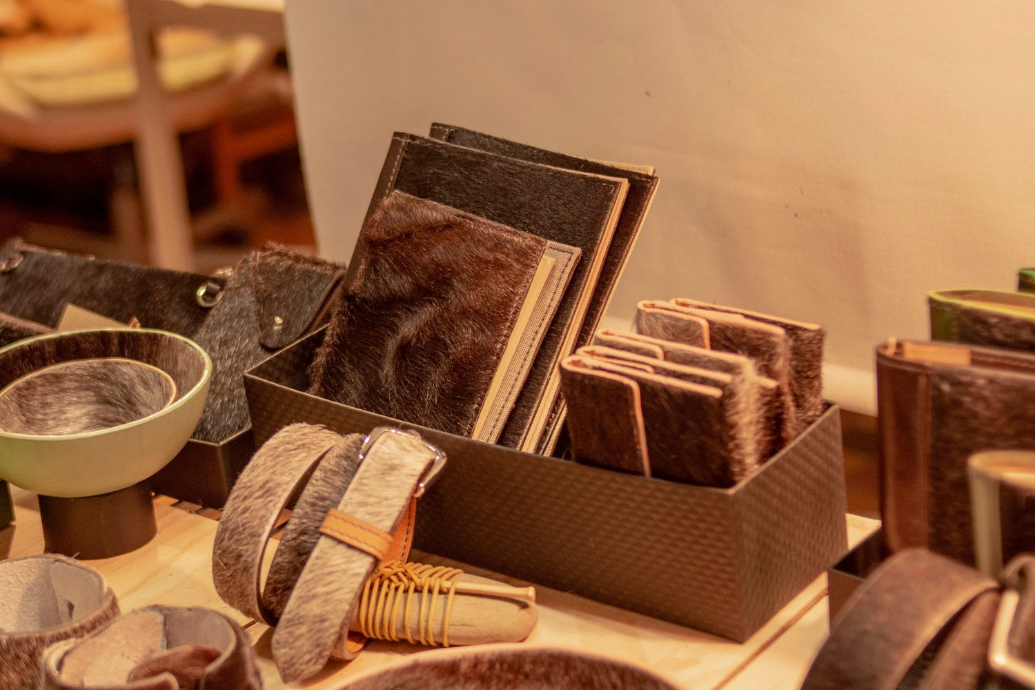 Notebooks covered in leather offcuts, with cuffs and key fobs cut from smaller scraps, set out on a table at Rowan & Reed