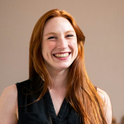 Dorothy Murphy, Product Designer at Unapp, smiling beside a whiteboard of sketches in the office