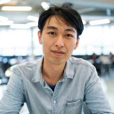 James Carter, Lead Engineer at Unapp, in a denim shirt smiling at his desk in a bright open-plan office