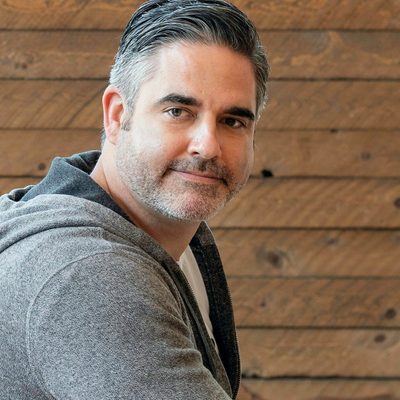 Leo Novak, Customer Success at Unapp, a grey-haired man in a grey hoodie smiling at his desk