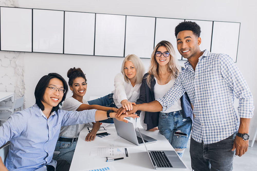 Colleagues stacking their hands together over a desk in an office