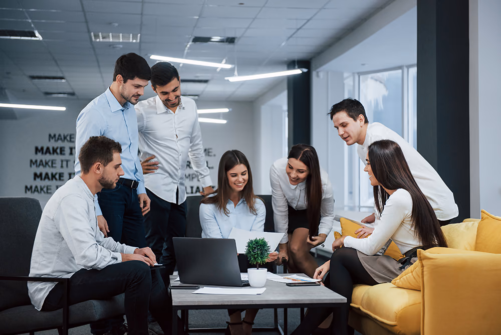 A team gathered around laptops in a bright office